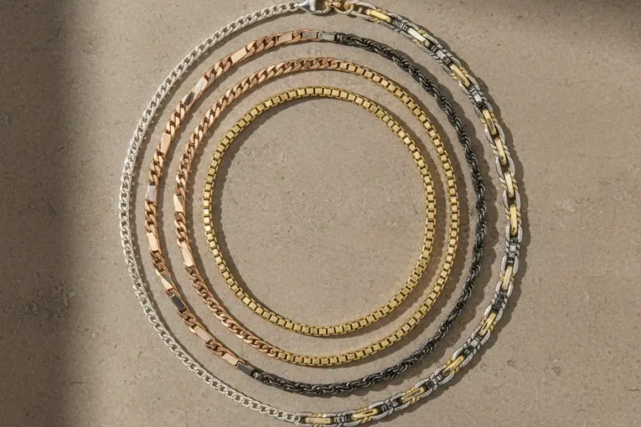 Best jewelry chain styles displayed in a premium editorial flat lay with cable curb box rope and figaro chains